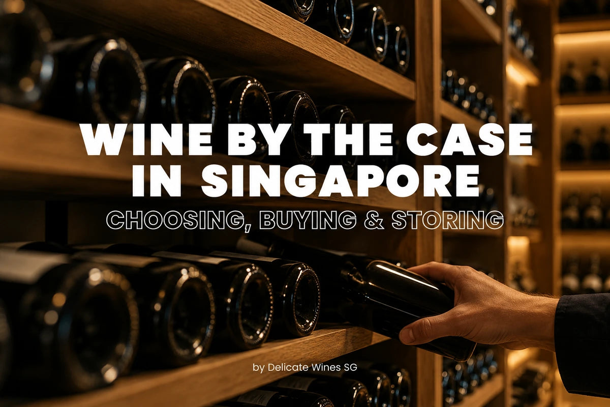 A hand holds a wine bottle on a wooden wine rack shelf, with many bottles stored in the background. Large overlaid text reads 'WINE BY THE CASE IN SINGAPORE' and 'CHOOSING, BUYING & STORING', with a smaller credit 'by Delicate Wines SG'.